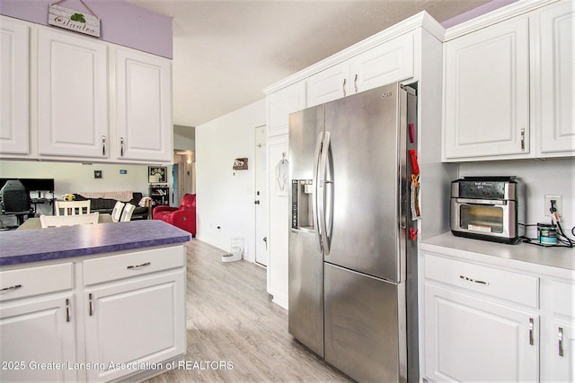 6093 Anchor Cv, Dimondale, MI 48821 - kitchen with stainless steel fridge with ice dispenser, white cabinetry, and light wood-style flooring