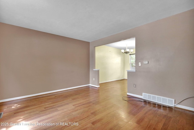6213 Beechfield Dr, Lansing, MI 48911 - empty room with wood finished floors and a chandelier