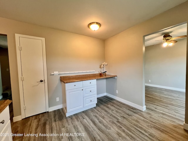 5401 Catalpa Dr, Lansing, MI 48911 - kitchen with wood finished floors, white cabinets, ceiling fan, built in study area, and dark countertops