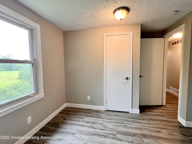 5401 Catalpa Dr, Lansing, MI 48911 - unfurnished bedroom featuring a textured ceiling and wood finished floors