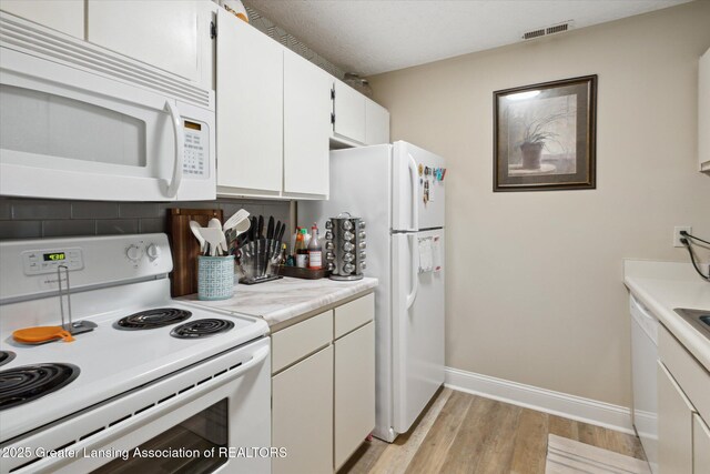 1457 E Pond Dr Unit 21, Okemos, MI 48864 - kitchen featuring white appliances, light wood-style flooring, light countertops, and white cabinetry