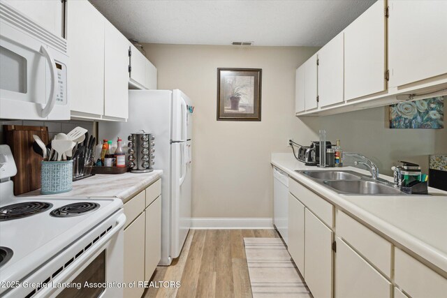 1457 E Pond Dr Unit 21, Okemos, MI 48864 - kitchen with white appliances, light wood finished floors, light countertops, and white cabinetry