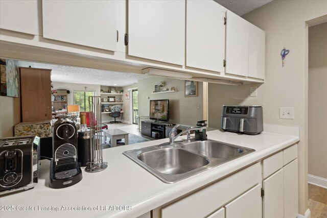 1457 E Pond Dr Unit 21, Okemos, MI 48864 - kitchen with light countertops, white cabinetry, open floor plan, and a textured ceiling