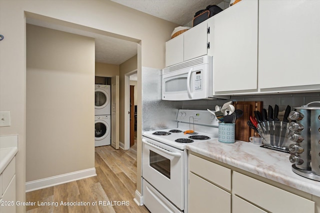 1457 E Pond Dr Unit 21, Okemos, MI 48864 - kitchen with white appliances, stacked washer / drying machine, light countertops, light wood-style floors, and white cabinetry