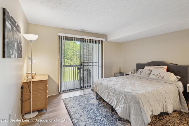 1457 E Pond Dr Unit 21, Okemos, MI 48864 - bedroom with access to exterior, wood finished floors, and a textured ceiling