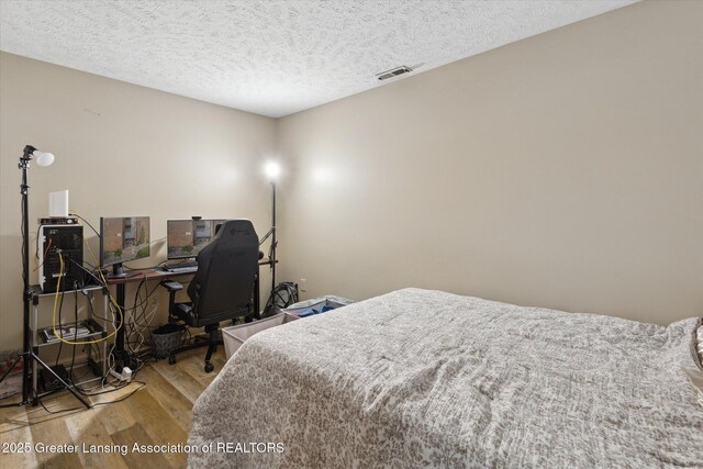 1457 E Pond Dr Unit 21, Okemos, MI 48864 - bedroom featuring wood finished floors, a textured ceiling, and an office area