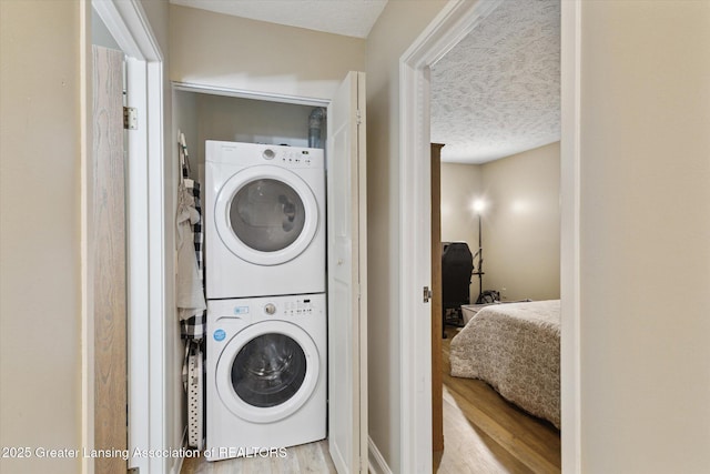 1457 E Pond Dr Unit 21, Okemos, MI 48864 - laundry area featuring estacked washer and dryer, wood finished floors, and a textured ceiling
