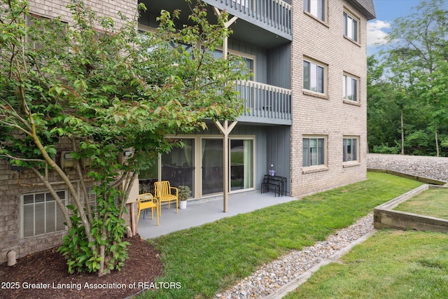 2926 Mount Hope Rd Unit 105, Okemos, MI 48864 - back of house featuring a balcony, a lawn, a patio area, brick siding, and board and batten siding
