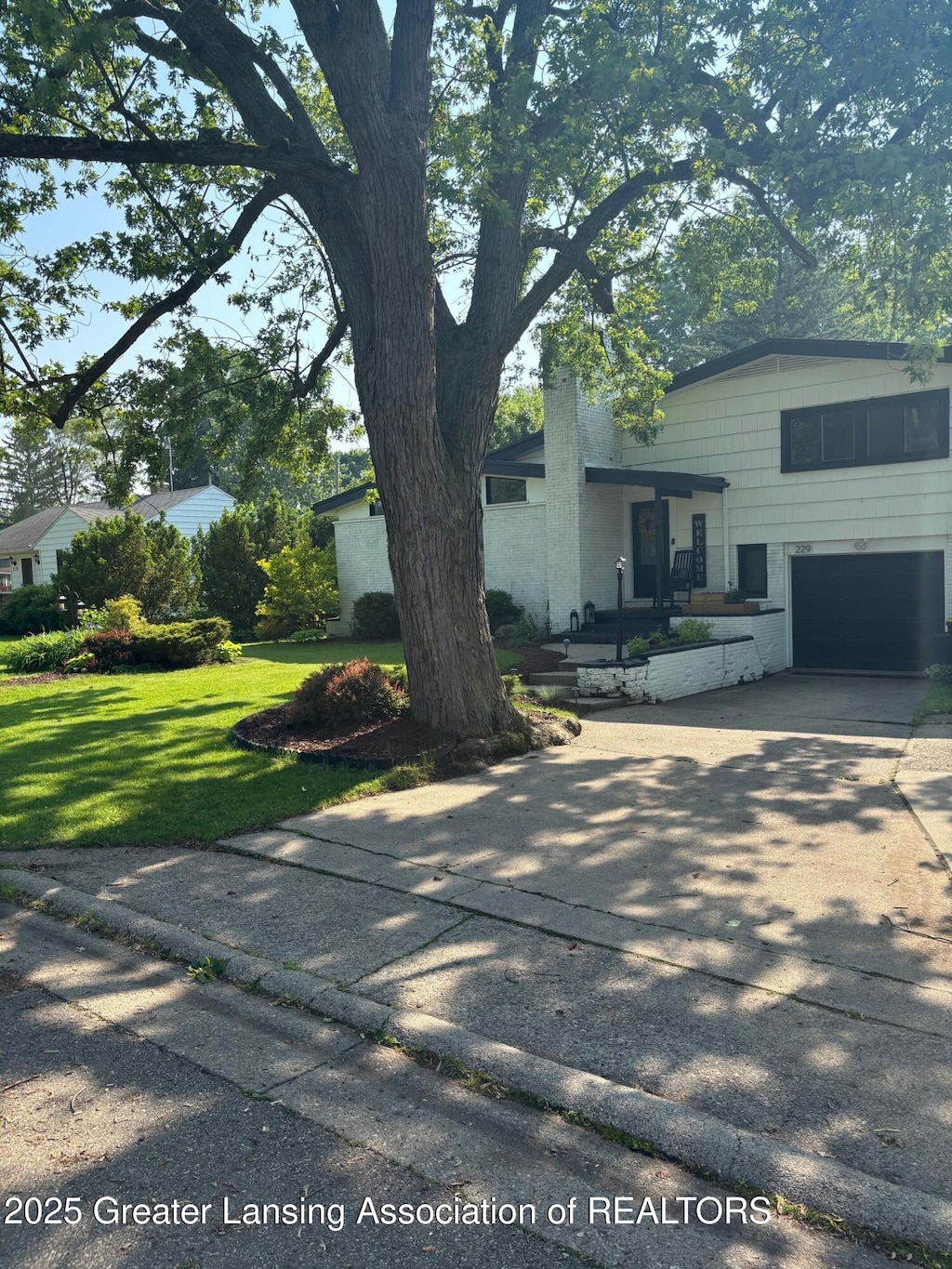 229 Julian Ave, Lansing, MI 48917 - view of front of property with a garage, a front yard, and concrete driveway