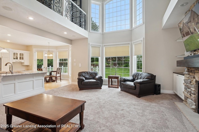 4700 Canyon Trl, Lansing, MI 48917 - living area featuring light colored carpet, a fireplace, a towering ceiling, a chandelier, and recessed lighting