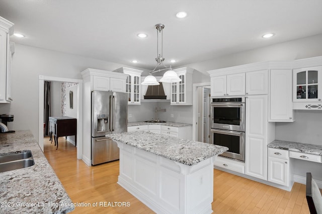 4700 Canyon Trl, Lansing, MI 48917 - kitchen with stainless steel appliances, white cabinets, a center island, light wood-style flooring, and hanging light fixtures