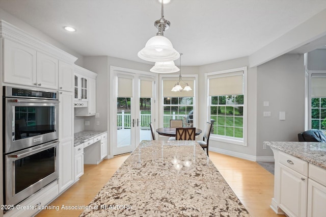 4700 Canyon Trl, Lansing, MI 48917 - kitchen with stainless steel double oven, white cabinets, a chandelier, light stone countertops, and decorative light fixtures