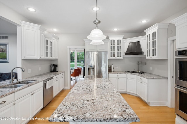 4700 Canyon Trl, Lansing, MI 48917 - kitchen featuring appliances with stainless steel finishes, custom exhaust hood, a center island, light wood-type flooring, and white cabinets