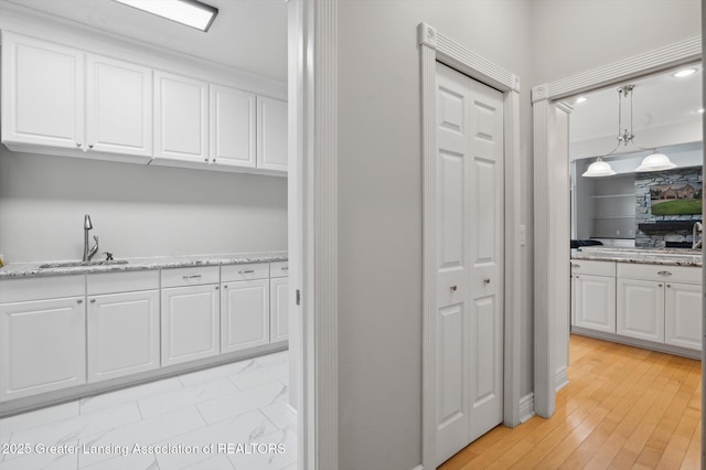 4700 Canyon Trl, Lansing, MI 48917 - kitchen featuring white cabinetry, light stone counters, and light wood-type flooring