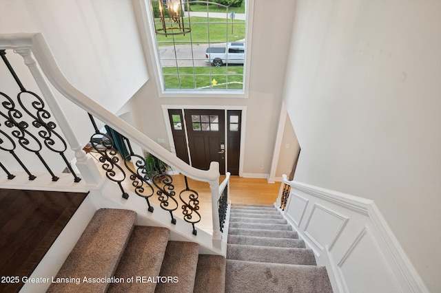 4700 Canyon Trl, Lansing, MI 48917 - foyer featuring stairway, a towering ceiling, wood finished floors, wainscoting, and a decorative wall