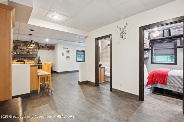 4700 Canyon Trl, Lansing, MI 48917 - interior space featuring a drop ceiling, dark wood-style floors, a fireplace, hanging light fixtures, and a breakfast bar
