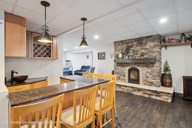 4700 Canyon Trl, Lansing, MI 48917 - kitchen featuring a paneled ceiling, dark wood-type flooring, open floor plan, a fireplace, and hanging light fixtures