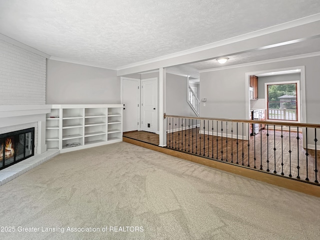 1869 E Burrwood Cir, East Lansing, MI 48823 - unfurnished living room with a brick fireplace, a textured ceiling, ornamental molding, and carpet floors