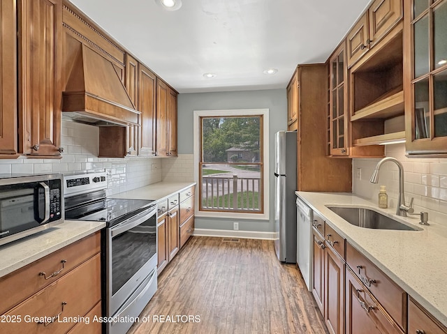 1869 E Burrwood Cir, East Lansing, MI 48823 - kitchen featuring appliances with stainless steel finishes, custom range hood, brown cabinets, and recessed lighting