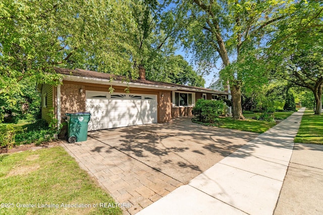522 Cowley Ave, East Lansing, MI 48823 - view of front facade with concrete driveway, brick siding, a garage, and a front lawn