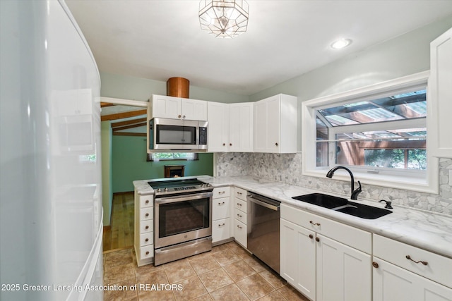 522 Cowley Ave, East Lansing, MI 48823 - kitchen featuring appliances with stainless steel finishes, white cabinets, backsplash, and light stone countertops