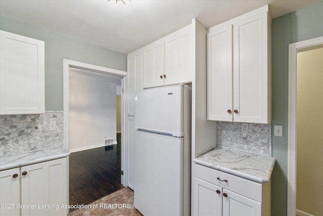 522 Cowley Ave, East Lansing, MI 48823 - kitchen with freestanding refrigerator, white cabinets, decorative backsplash, and light stone countertops