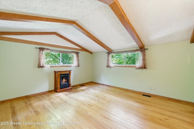 522 Cowley Ave, East Lansing, MI 48823 - unfurnished living room featuring a warm lit fireplace, plenty of natural light, a textured ceiling, and hardwood / wood-style flooring