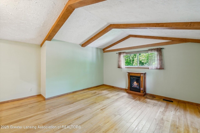 522 Cowley Ave, East Lansing, MI 48823 - unfurnished living room with a glass covered fireplace, hardwood / wood-style flooring, lofted ceiling, and a textured ceiling