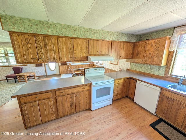 4963 E Portland Rd, Portland, MI 48875 - kitchen featuring white appliances, wallpapered walls, brown cabinetry, under cabinet range hood, and light wood finished floors