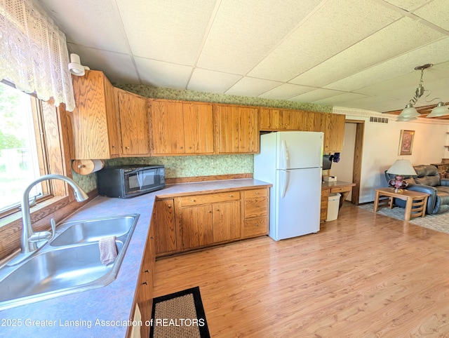 4963 E Portland Rd, Portland, MI 48875 - kitchen with freestanding refrigerator, black microwave, light wood-type flooring, a drop ceiling, and light countertops