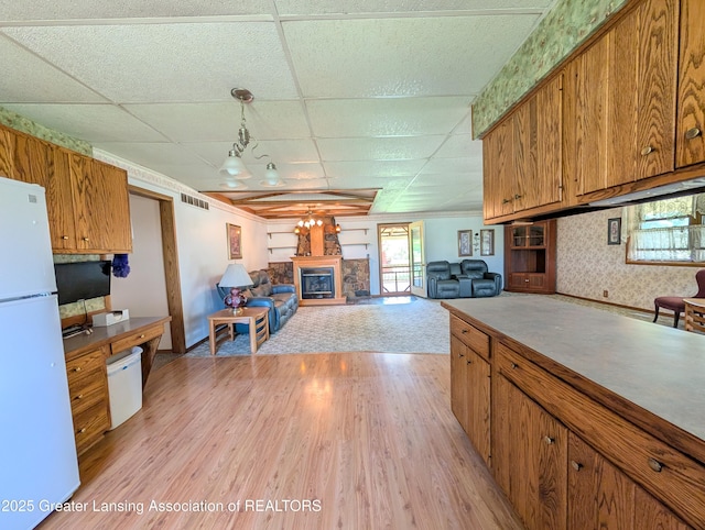 4963 E Portland Rd, Portland, MI 48875 - kitchen featuring freestanding refrigerator, brown cabinetry, a drop ceiling, light wood finished floors, and decorative light fixtures