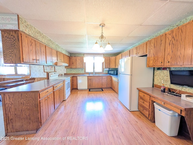 4963 E Portland Rd, Portland, MI 48875 - kitchen with white appliances, light wood-style floors, brown cabinetry, pendant lighting, and a drop ceiling