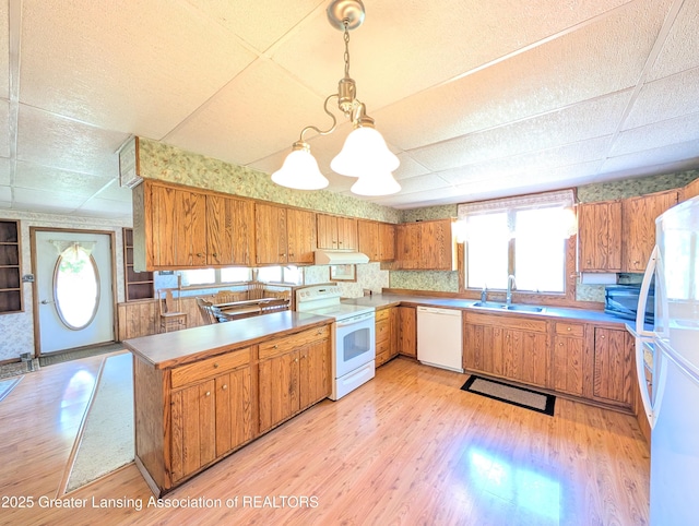 4963 E Portland Rd, Portland, MI 48875 - kitchen with white appliances, under cabinet range hood, a chandelier, light wood-type flooring, and brown cabinets