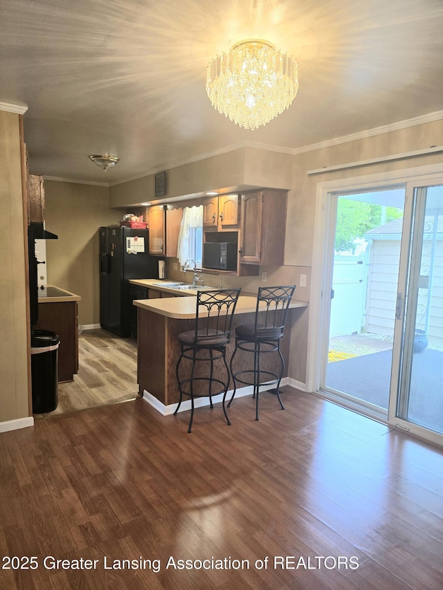3701 Sumpter St, Lansing, MI 48911 - kitchen featuring a peninsula, ornamental molding, wood finished floors, a chandelier, and freestanding refrigerator