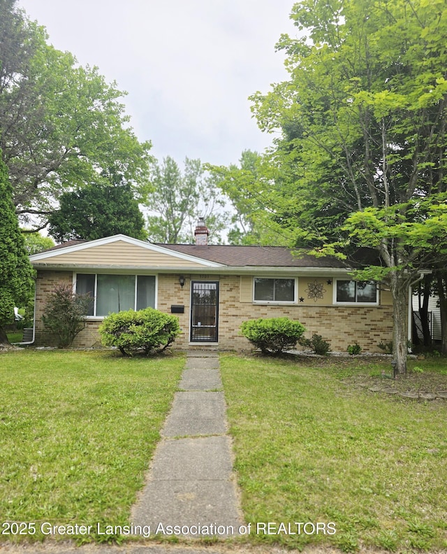3701 Sumpter St, Lansing, MI 48911 - ranch-style house featuring a chimney, a front yard, and brick siding