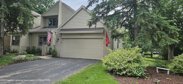 1945 W Danbury, Okemos, MI 48864 - view of front of house featuring brick siding, asphalt driveway, and a garage