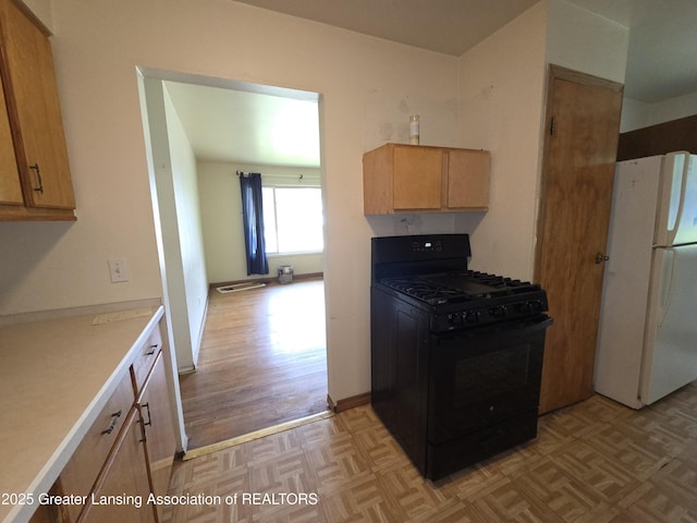 3629 Alpine Dr, Lansing, MI 48911 - kitchen with freestanding refrigerator, black range with gas cooktop, light countertops, and parquet floors