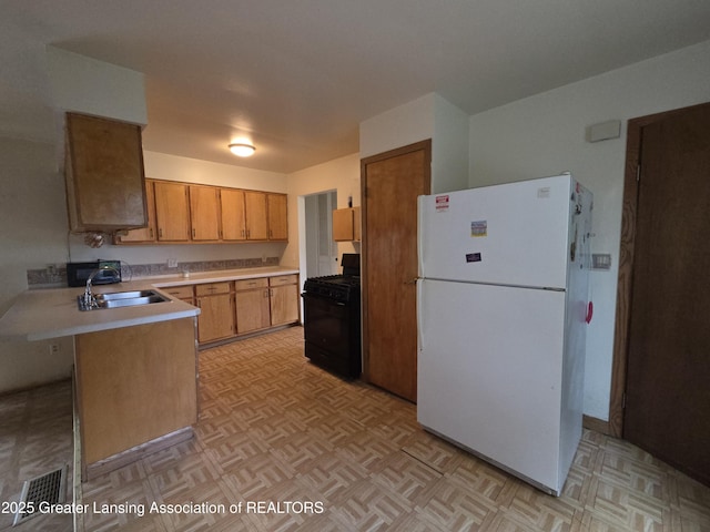3629 Alpine Dr, Lansing, MI 48911 - kitchen featuring freestanding refrigerator, gas stove, light countertops, a peninsula, and brown cabinets