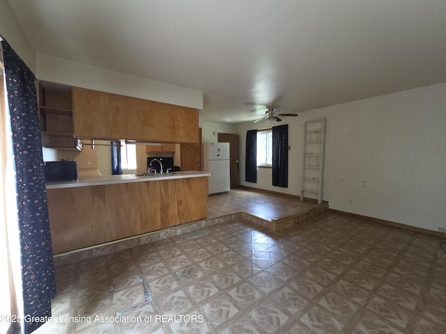 3629 Alpine Dr, Lansing, MI 48911 - kitchen with freestanding refrigerator, ceiling fan, brown cabinets, a peninsula, and light countertops