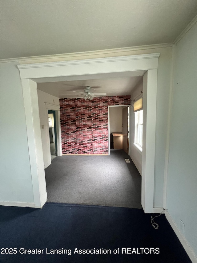 909 Baker St, Lansing, MI 48910 - empty room with brick wall, dark carpet, and ceiling fan