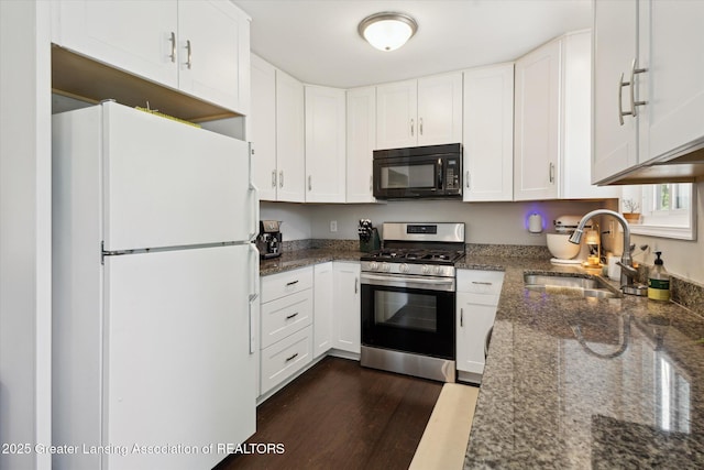 1539 Jacqueline Dr, Holt, MI 48842 - kitchen with freestanding refrigerator, black microwave, stainless steel gas range oven, dark stone counters, and dark wood-style flooring