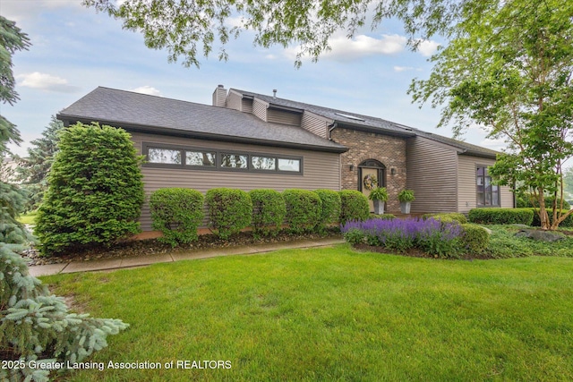 4925 Aspen Dr, Lansing, MI 48917 - view of front facade featuring a front lawn, a chimney, and roof with shingles