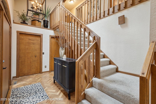 4925 Aspen Dr, Lansing, MI 48917 - stairway featuring a textured wall and a chandelier