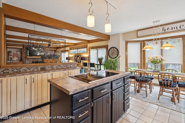 4925 Aspen Dr, Lansing, MI 48917 - kitchen featuring black electric stovetop, light tile patterned floors, beam ceiling, a kitchen island, and a chandelier