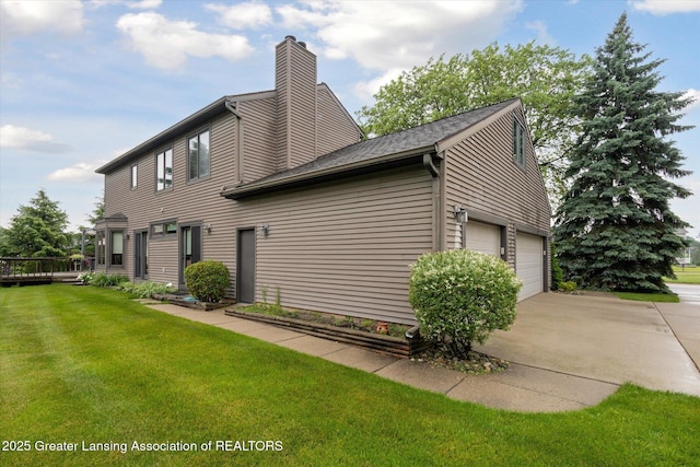 4925 Aspen Dr, Lansing, MI 48917 - rear view of property featuring a chimney, a garage, a lawn, driveway, and roof with shingles