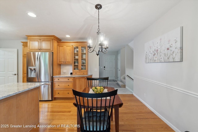 6252 N River Hwy, Grand Ledge, MI 48837 - kitchen featuring stainless steel fridge, a chandelier, glass insert cabinets, decorative light fixtures, and light wood-type flooring