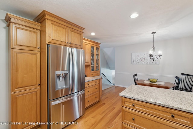 6252 N River Hwy, Grand Ledge, MI 48837 - kitchen with stainless steel fridge with ice dispenser, light wood-style flooring, glass insert cabinets, light stone counters, and a chandelier