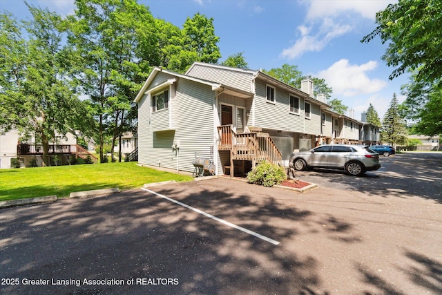 5041 E Willoughby Rd Unit 7, Holt, MI 48842 - view of front of house featuring a chimney, a front lawn, and uncovered parking