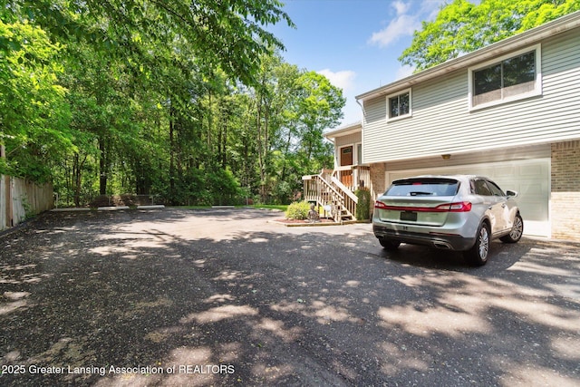 5041 E Willoughby Rd Unit 7, Holt, MI 48842 - view of property exterior featuring brick siding, driveway, an attached garage, and stairway