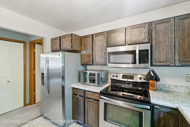 5041 E Willoughby Rd Unit 7, Holt, MI 48842 - kitchen with stainless steel appliances, dark brown cabinetry, and light stone countertops